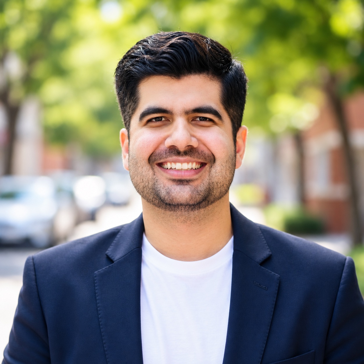 Haseeb Sultan smiling outdoors, wearing a navy blazer and white shirt